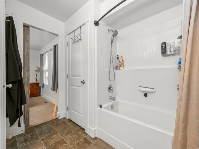 Full white shower-over-tub combination with chrome fixtures and integrated shelving
