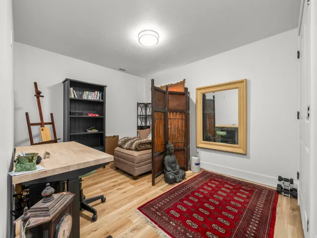 Versatile room featuring wood-finish flooring, a contemporary ceiling light fixture, and white wall finishes