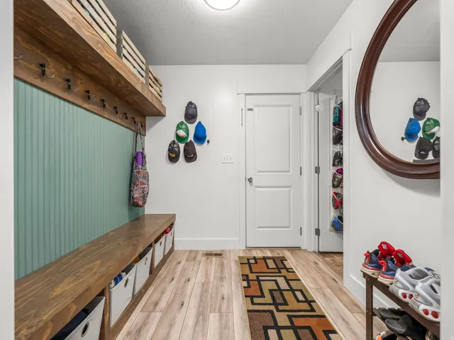 Entryway featuring wood-finish flooring, a built-in wooden bench with storage cubbies, and a coordinated wooden shelf with integrated coat hooks