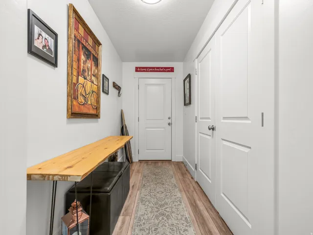 Hallway featuring light wood-finish flooring, white walls, and a white paneled door