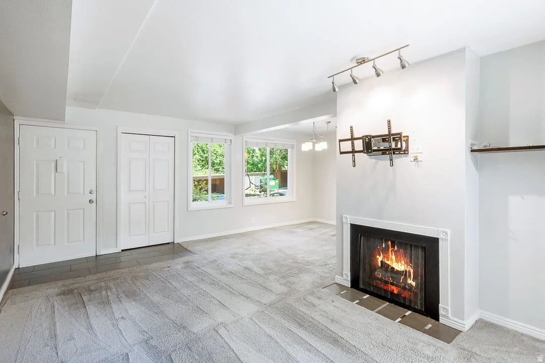 Living area featuring a fireplace with a white mantel, recessed shelving, track lighting, and two windows