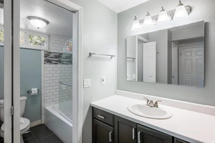 Bathroom featuring a dark wood-finish vanity with a white countertop, a rectangular mirror, and a four-light fixture
