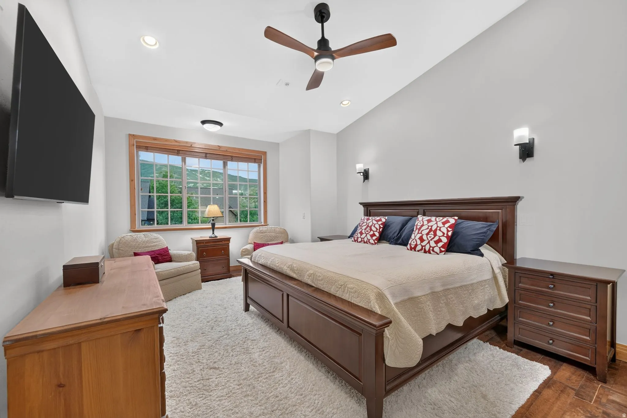 Spacious room featuring vaulted ceilings, recessed lighting, and a prominent window with wood-finish trim