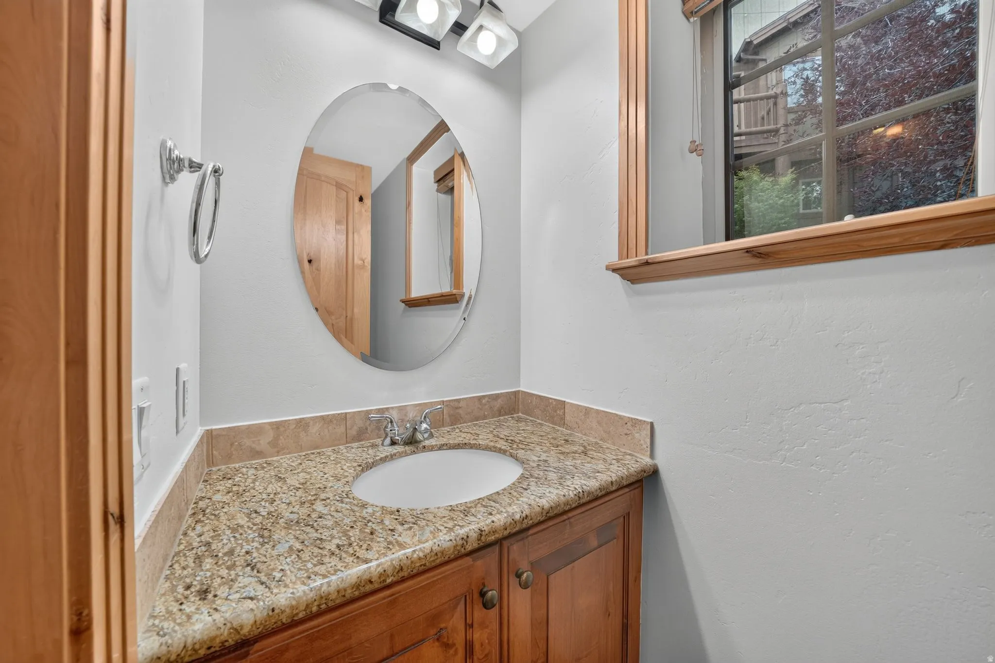 Bathroom vanity featuring a granite-style countertop, undermount sink, and wood-finish cabinetry