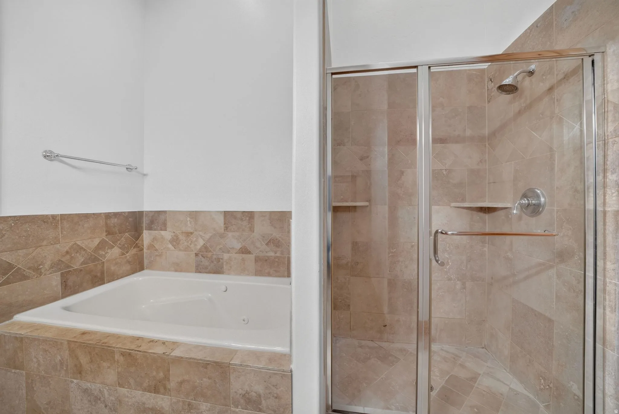 Bathroom featuring a tiled soaking tub and a separate glass-enclosed shower