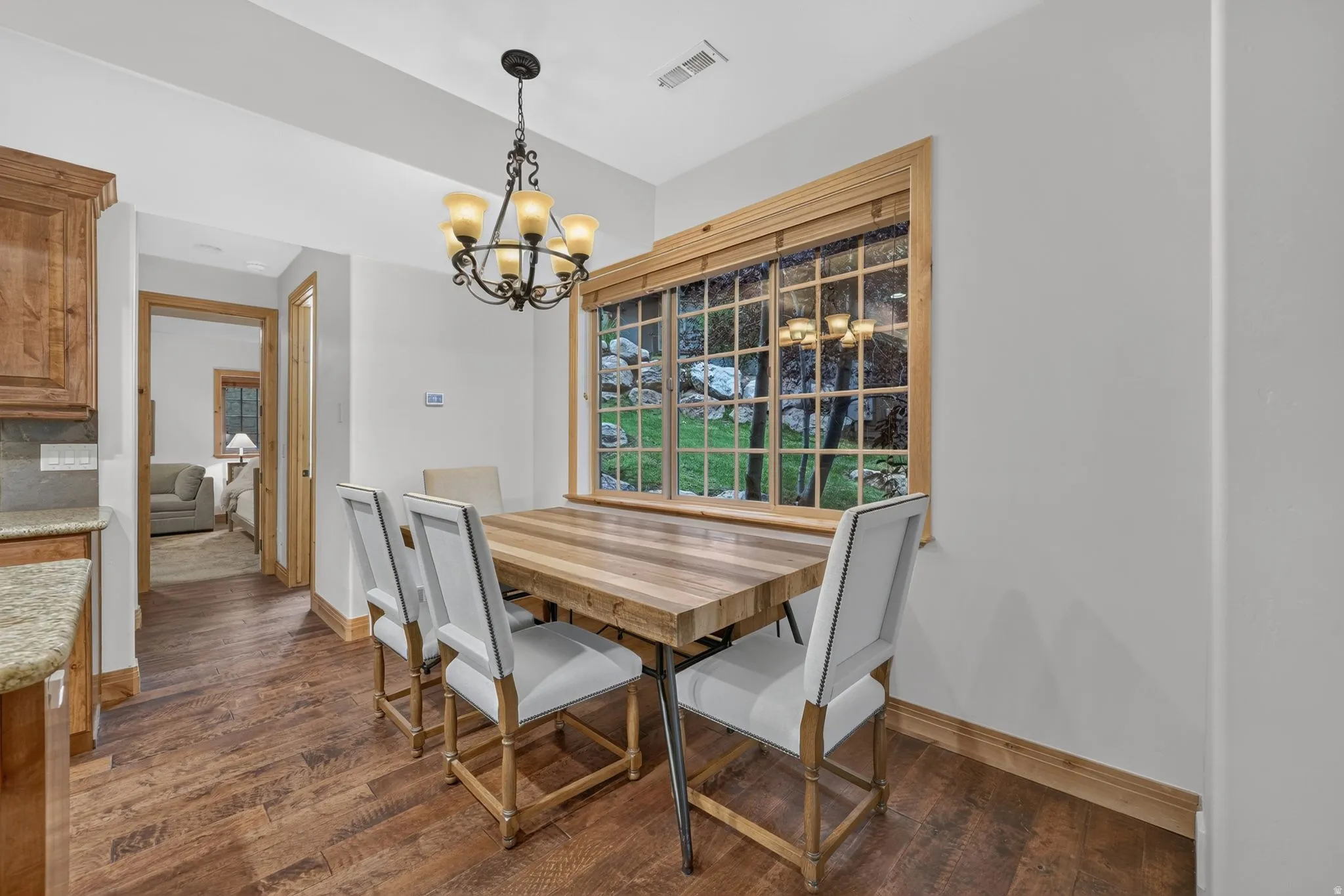 Dining area featuring a decorative chandelier, a large window with wood trim, and wood-finish flooring