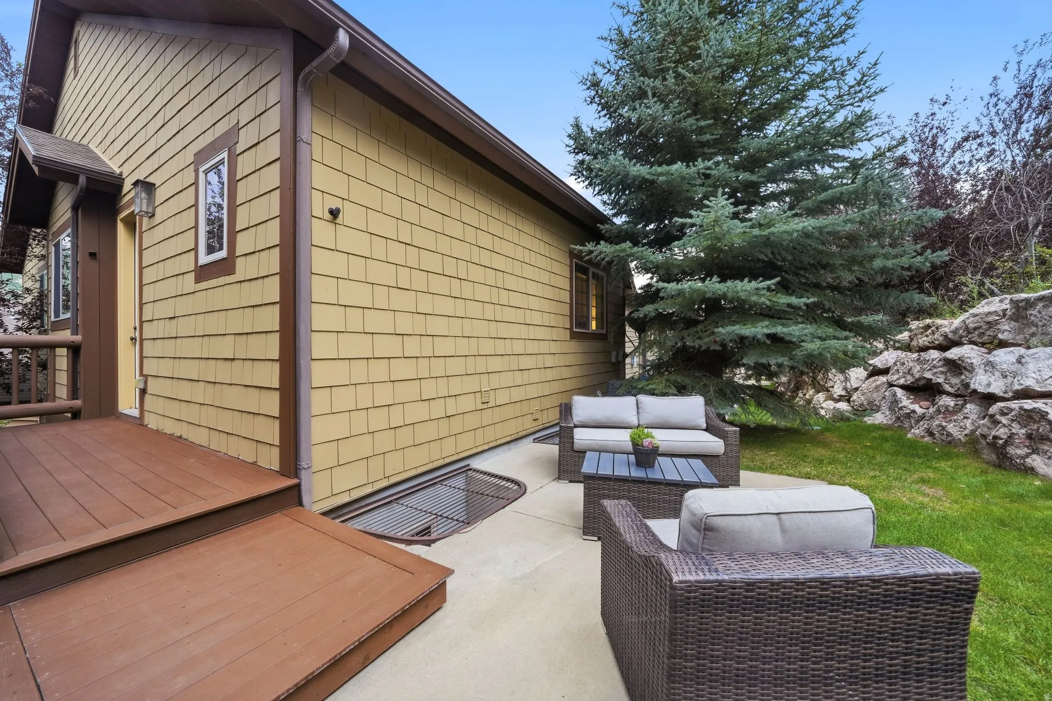 Exterior featuring shingle siding, a wooden deck, and a concrete patio