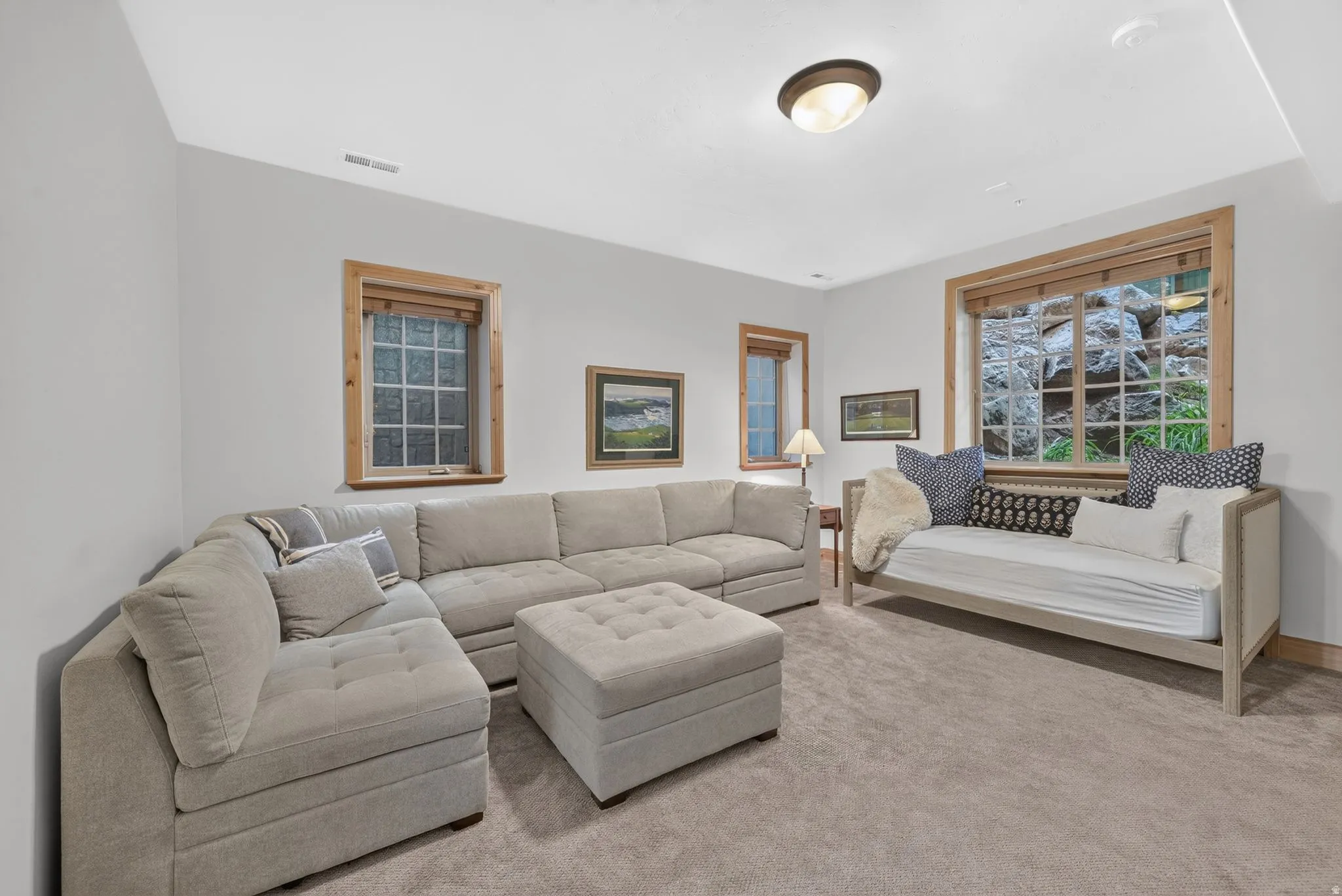 Neutral wall paint, light-toned carpeting, and natural wood window trim create a versatile interior space