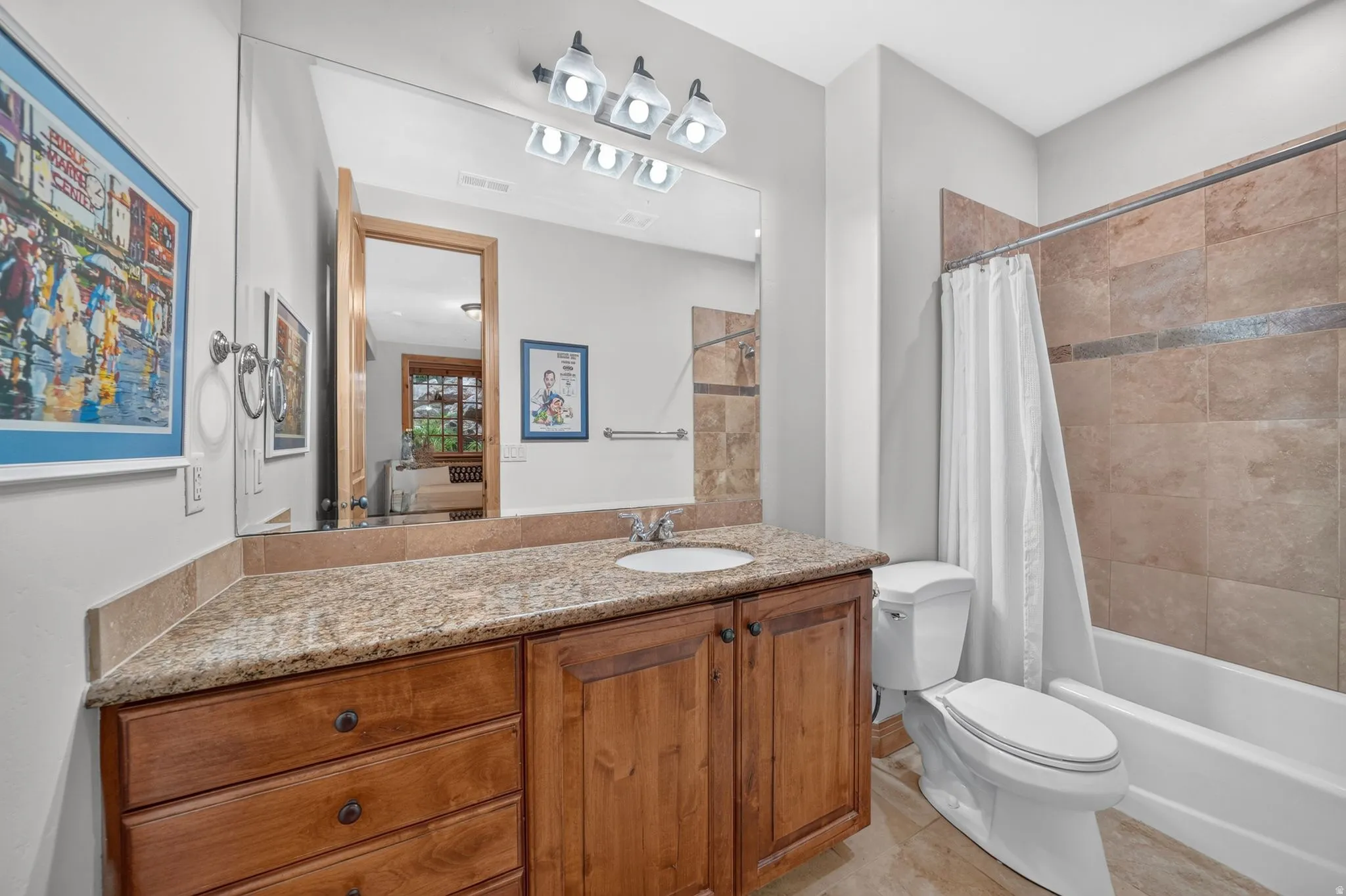 Bathroom featuring a wood-finish vanity with an integrated sink, a speckled countertop, and overhead vanity lighting