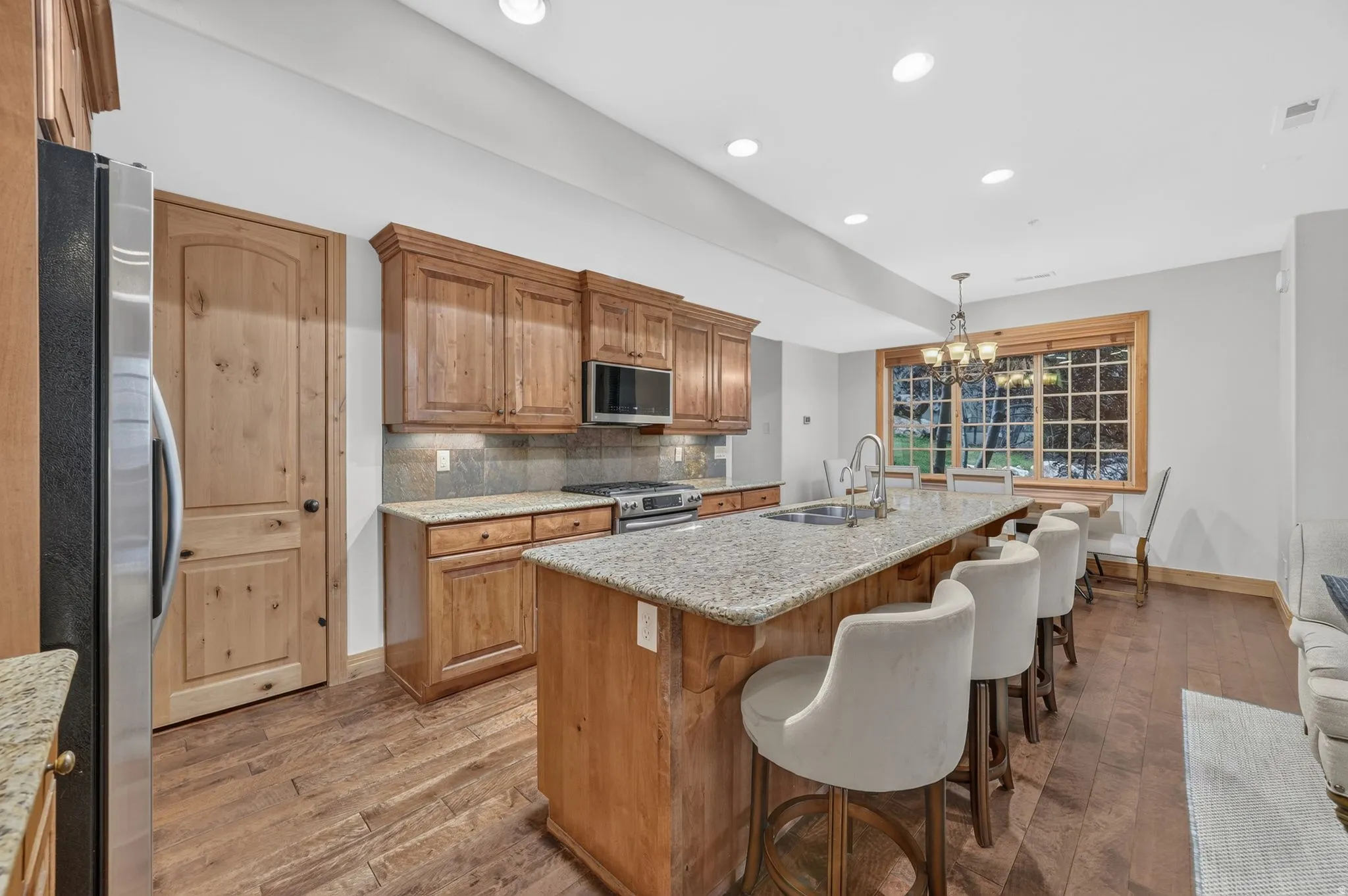 Kitchen featuring wood-finish flooring, recessed lighting, and a large central island with an undermount sink and granite countertop
