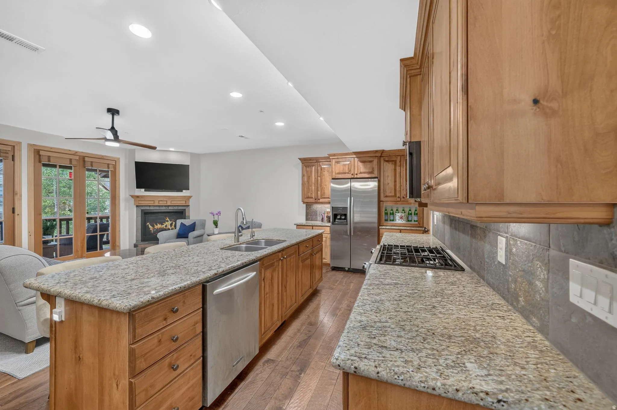 Open-concept kitchen featuring granite countertops, wood-finish flooring, and natural wood cabinetry
