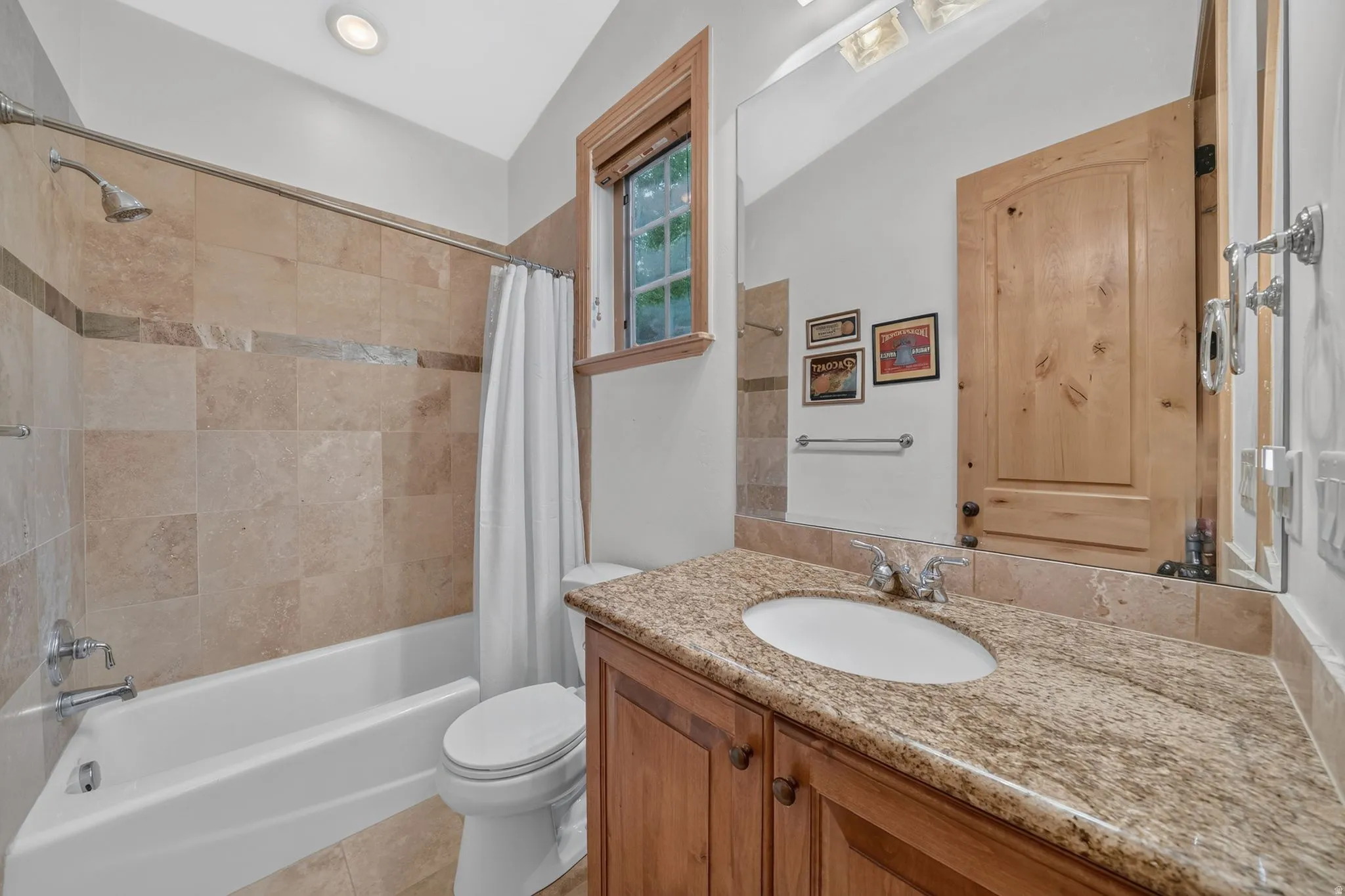 Bathroom featuring a wood vanity with a granite countertop, undermount sink, and chrome fixtures