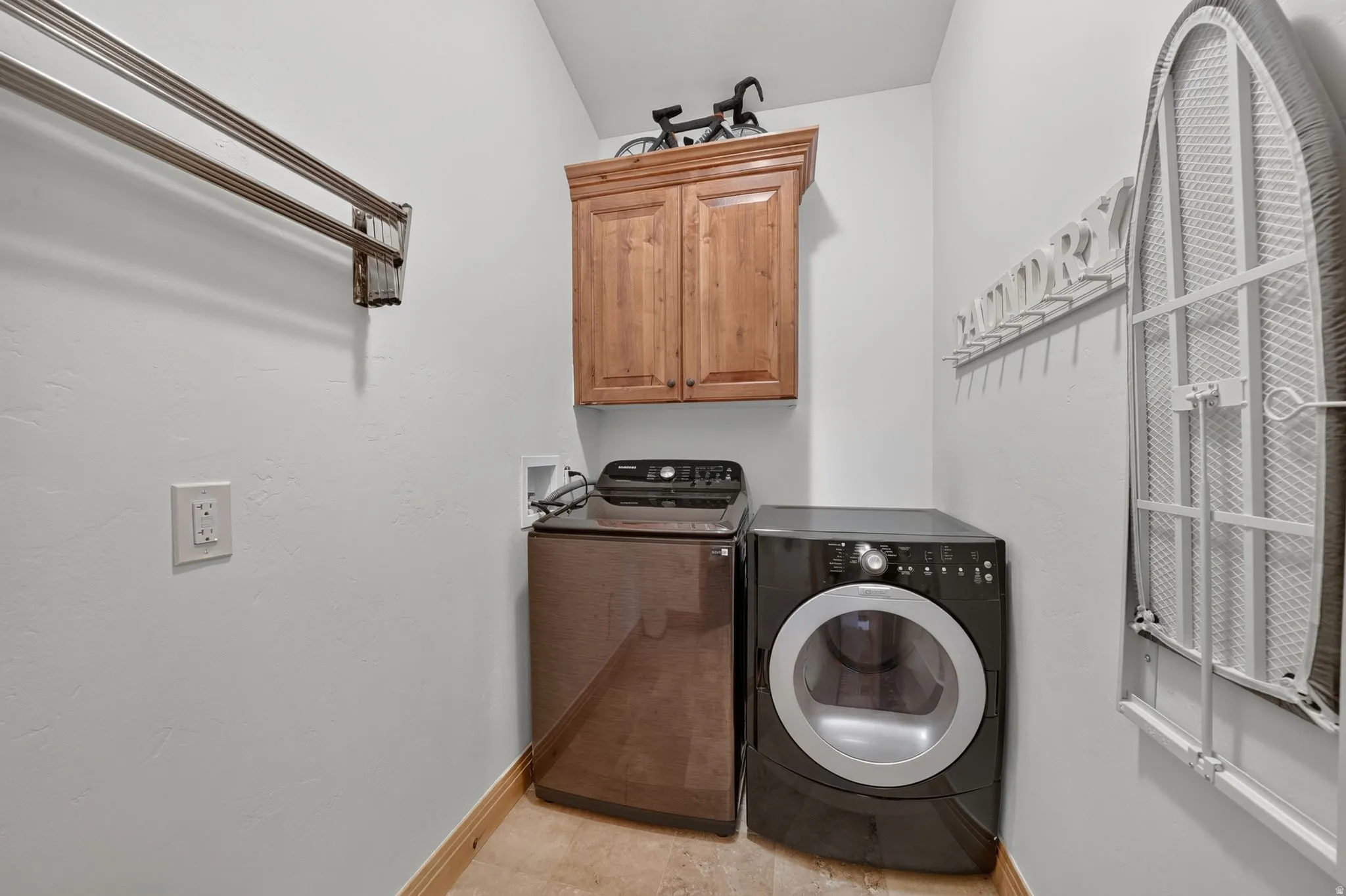 Dedicated utility room featuring light-toned walls, wood-finish baseboard trim, and tiled flooring