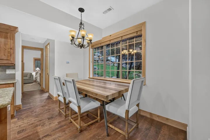 Dining area featuring a decorative chandelier, a large window with wood trim, and wood-finish flooring