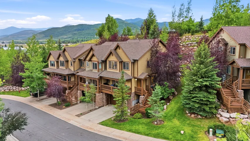 Townhome complex with stone pillar accents, wood-finish balconies, and a mountain backdrop