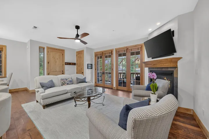 Living area featuring wood-finish flooring, a stone-clad fireplace with a wood mantel, and double French doors opening to an exterior space