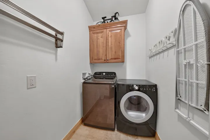 Dedicated utility room featuring light-toned walls, wood-finish baseboard trim, and tiled flooring