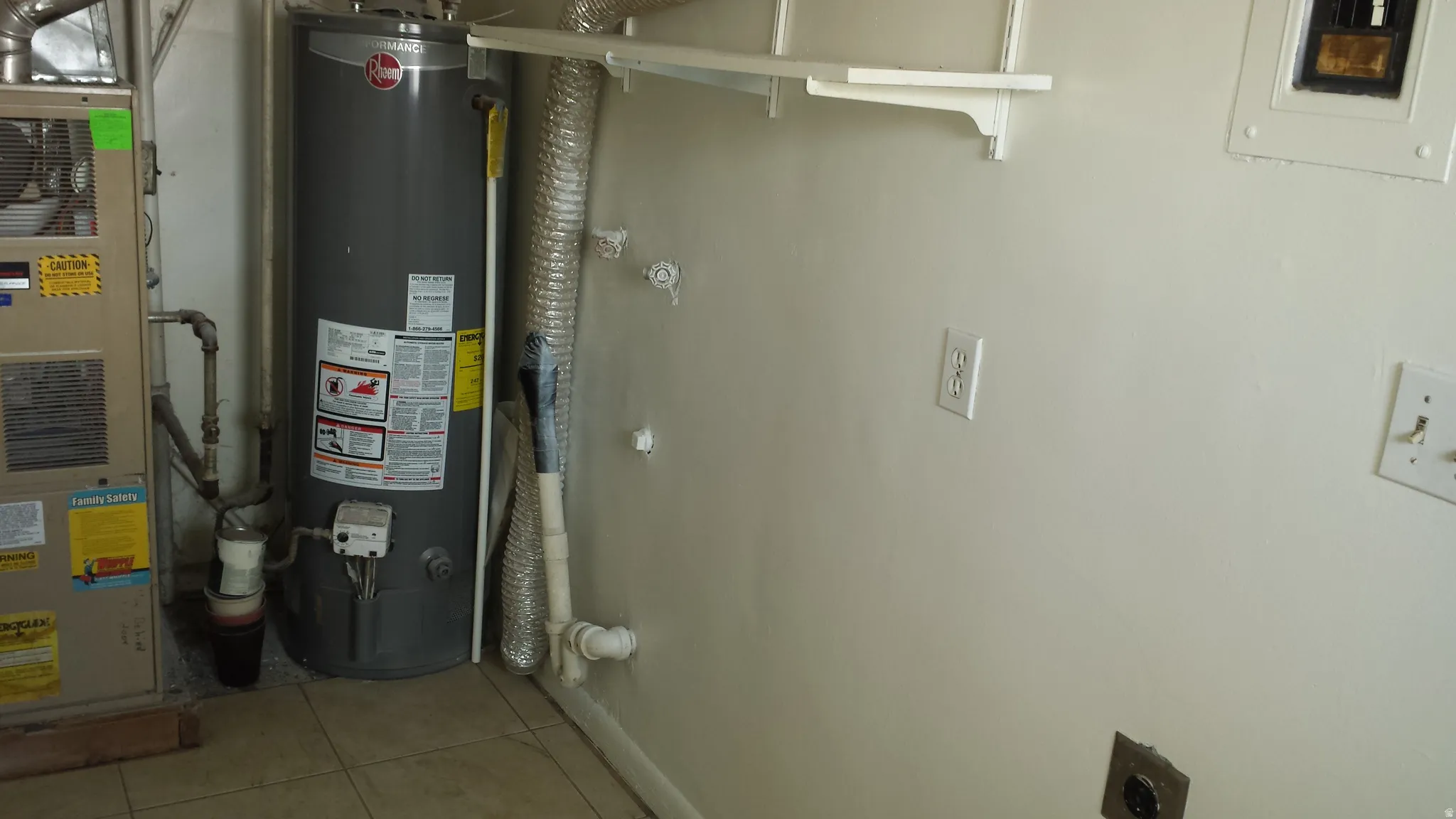 Utility area featuring a water heater, furnace, wall-mounted shelving, and tiled flooring