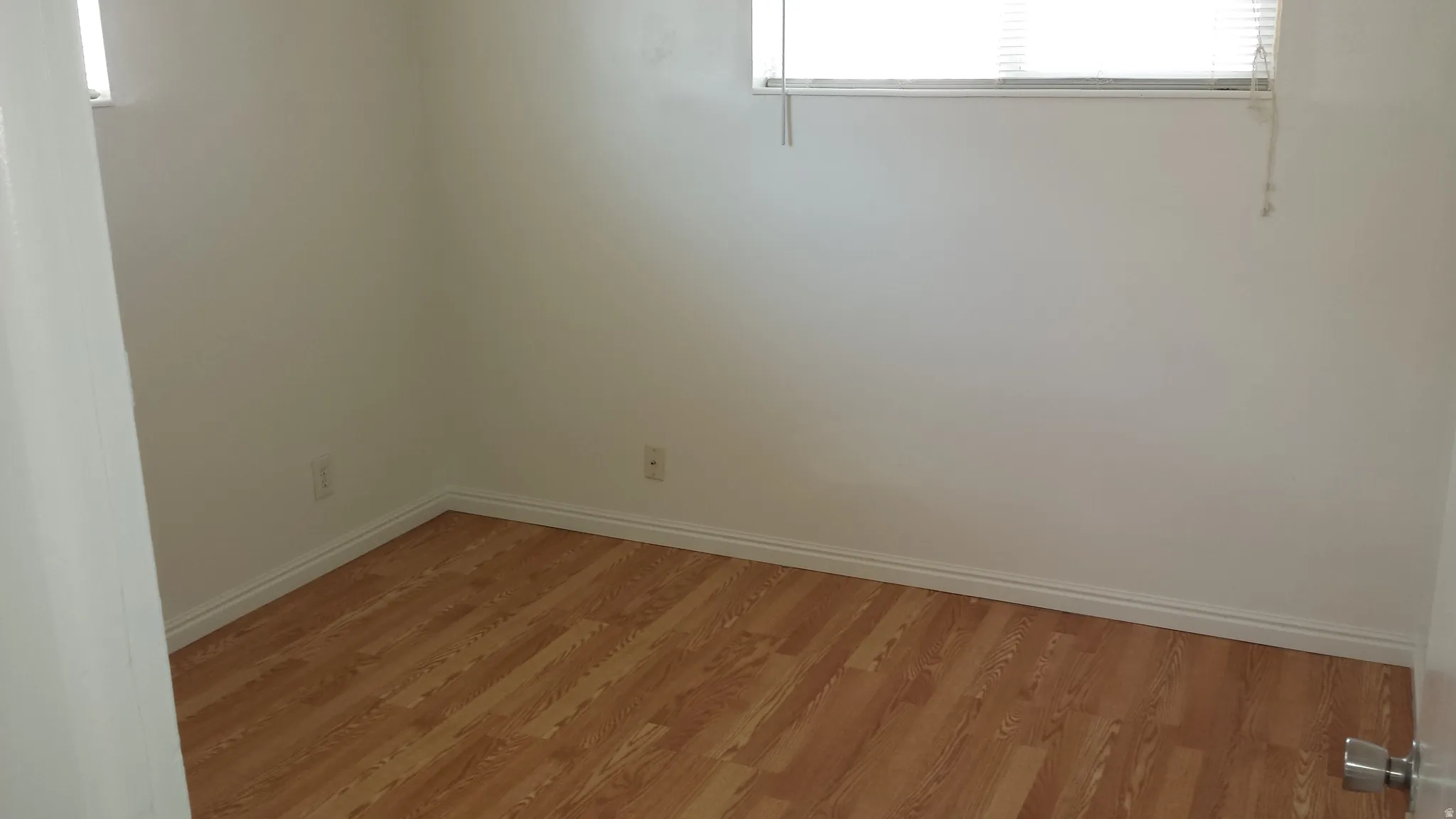 Bright interior room featuring wood-finish flooring, white baseboards, and white walls