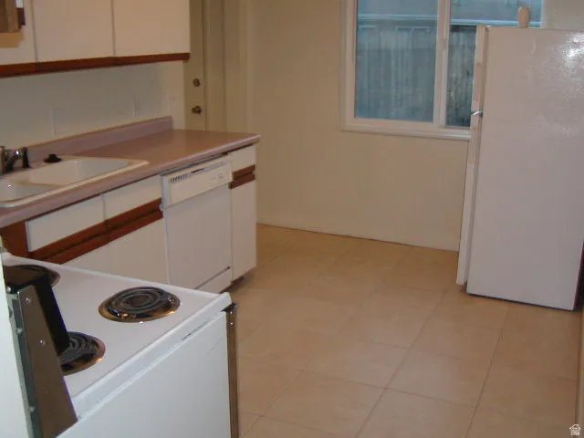 Kitchen with tile flooring featuring a white double-basin sink, a built-in dishwasher, and a white range
