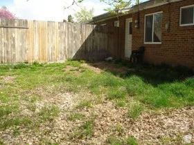 Private backyard space featuring a wood fence, red brick exterior, and a white entry door