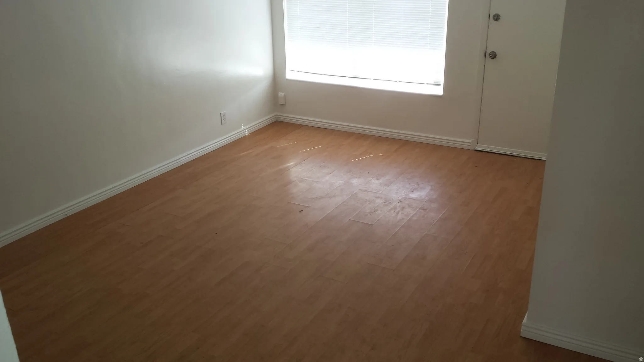Room with wood-finish flooring, white baseboards, and a window with blinds