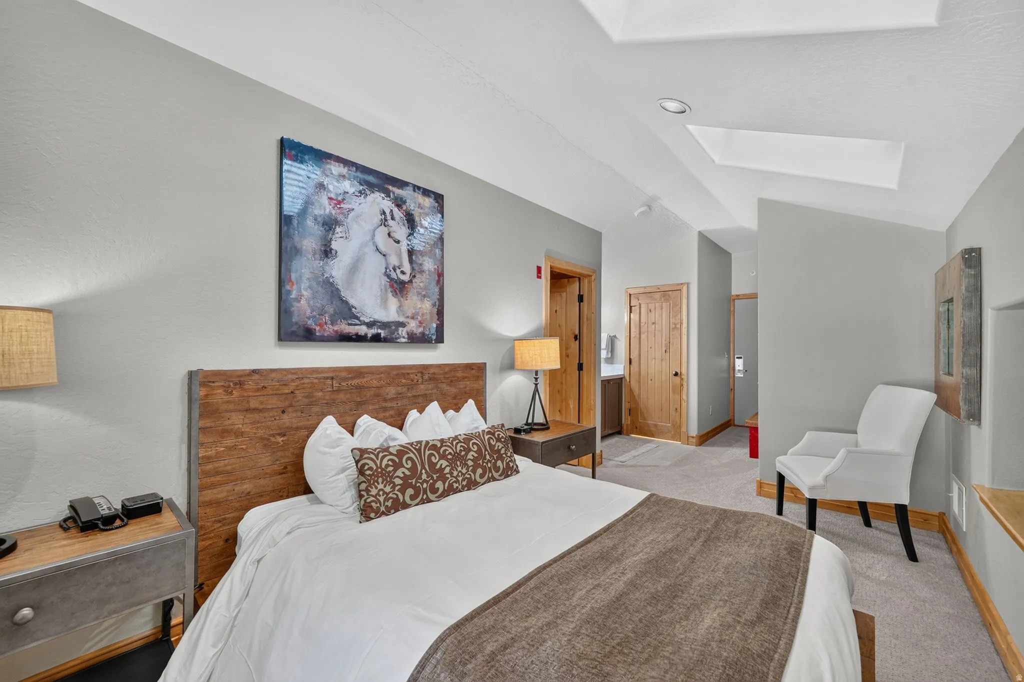 Light grey walls with a rustic wood-finish headboard and neutral-toned carpet flooring