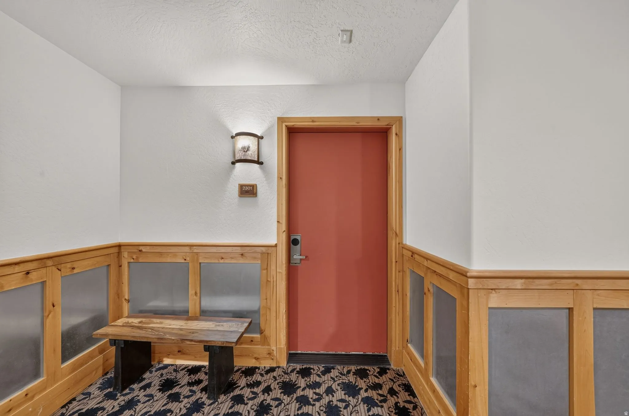 Wood-paneled wainscoting with frosted inserts, a distinctive wall-mounted sconce, and a patterned carpet