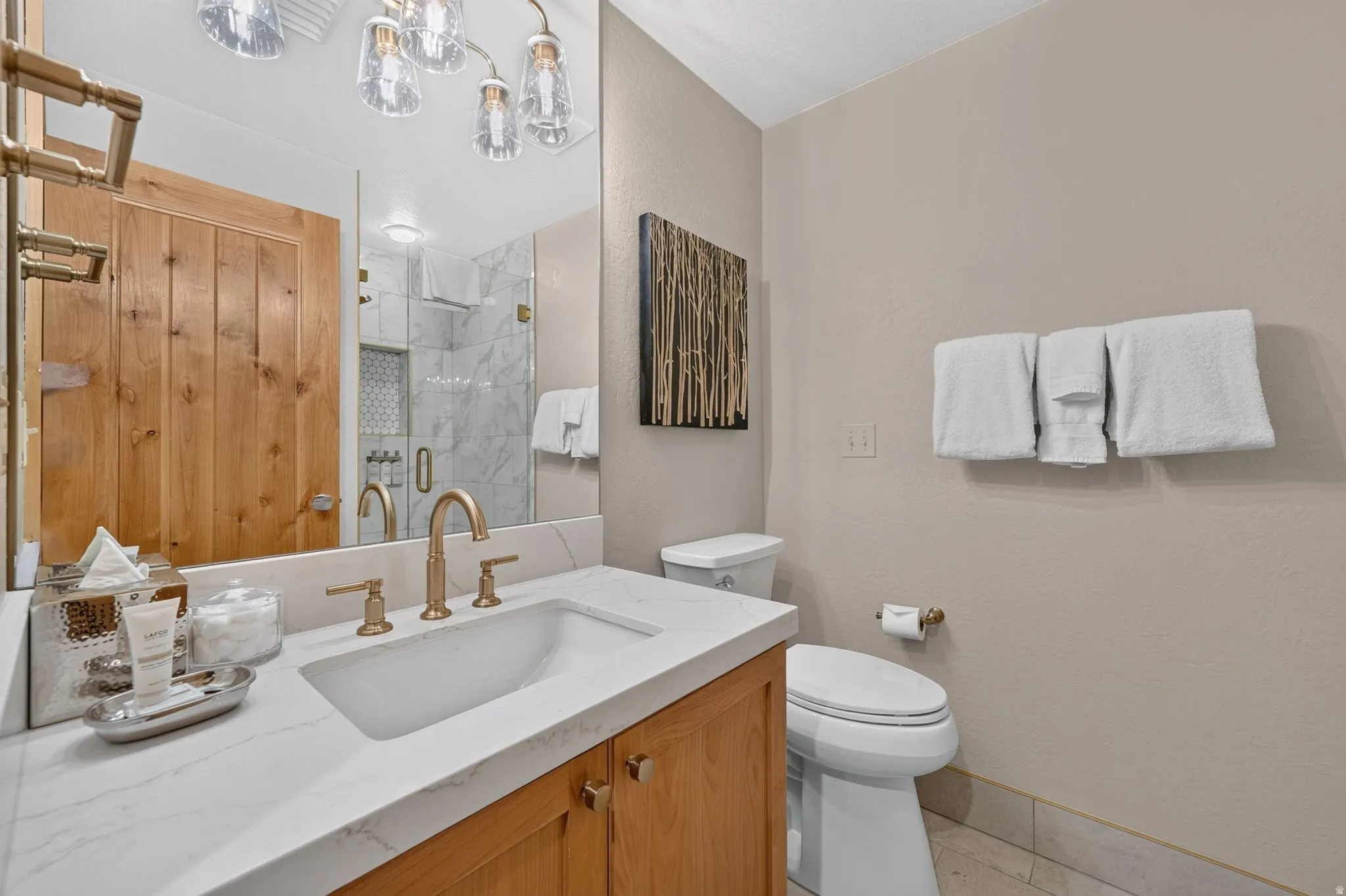 Bathroom featuring a light wood vanity with a white countertop, an undermount sink, and a gold-toned faucet