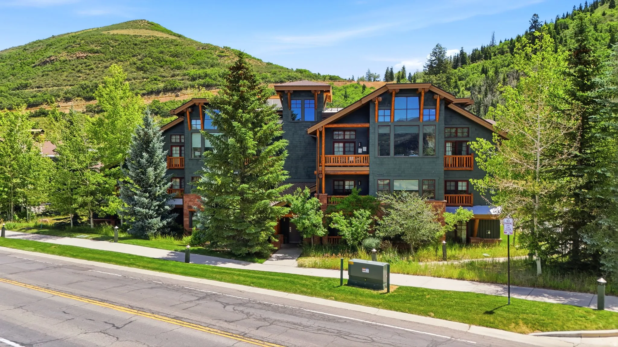 Multi-story property featuring a dark-toned facade, multiple balconies with wood railings, and expansive windows