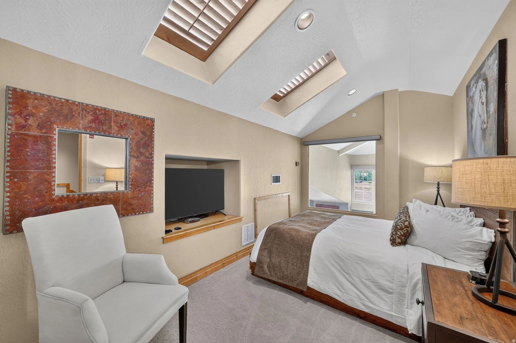 Bedroom with vaulted ceilings featuring two skylights with louvered blinds, recessed lighting, and built-in television niche
