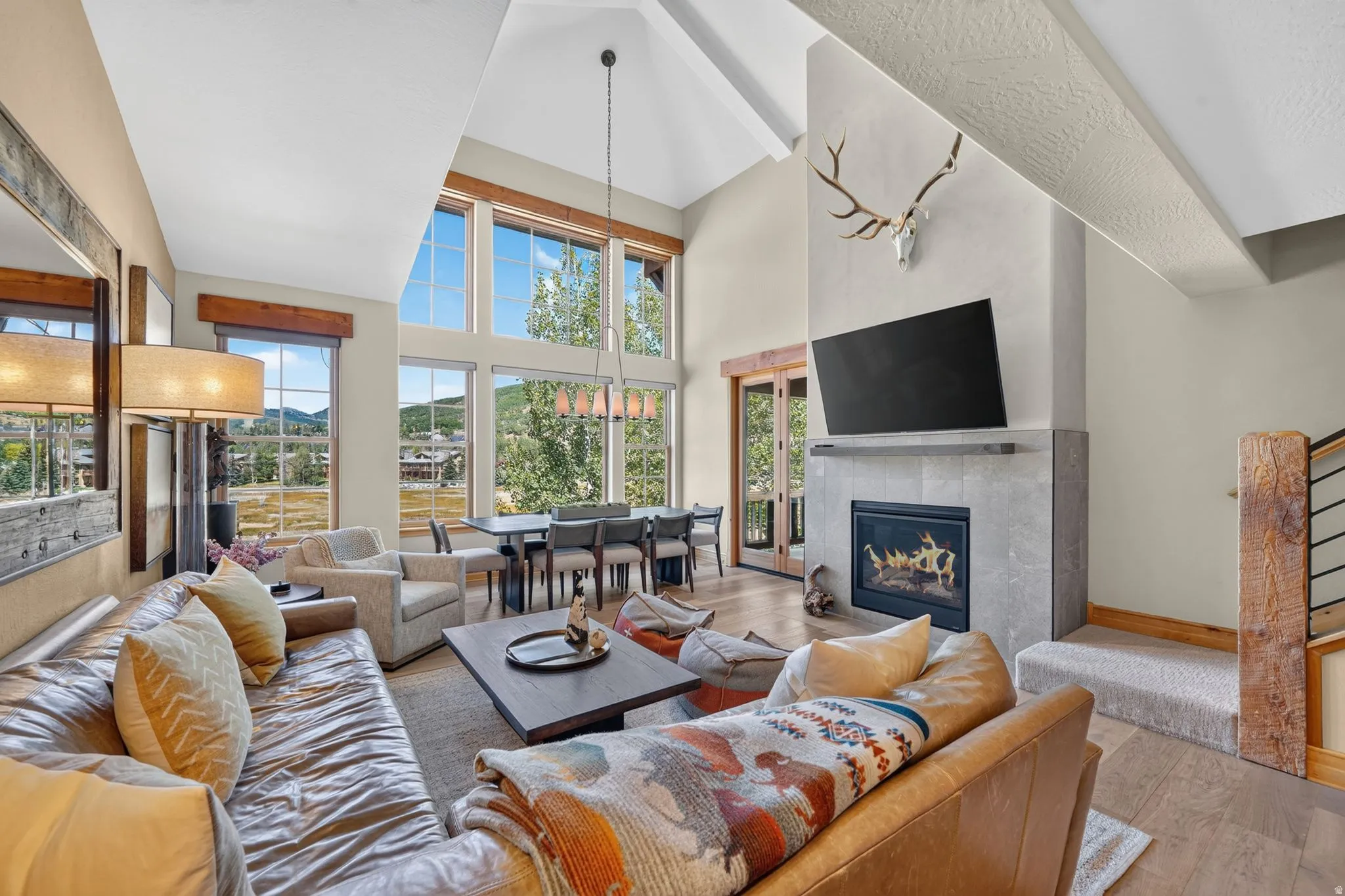 Vaulted ceilings complement the expansive window bank, showcasing a modern fireplace with a tiled surround