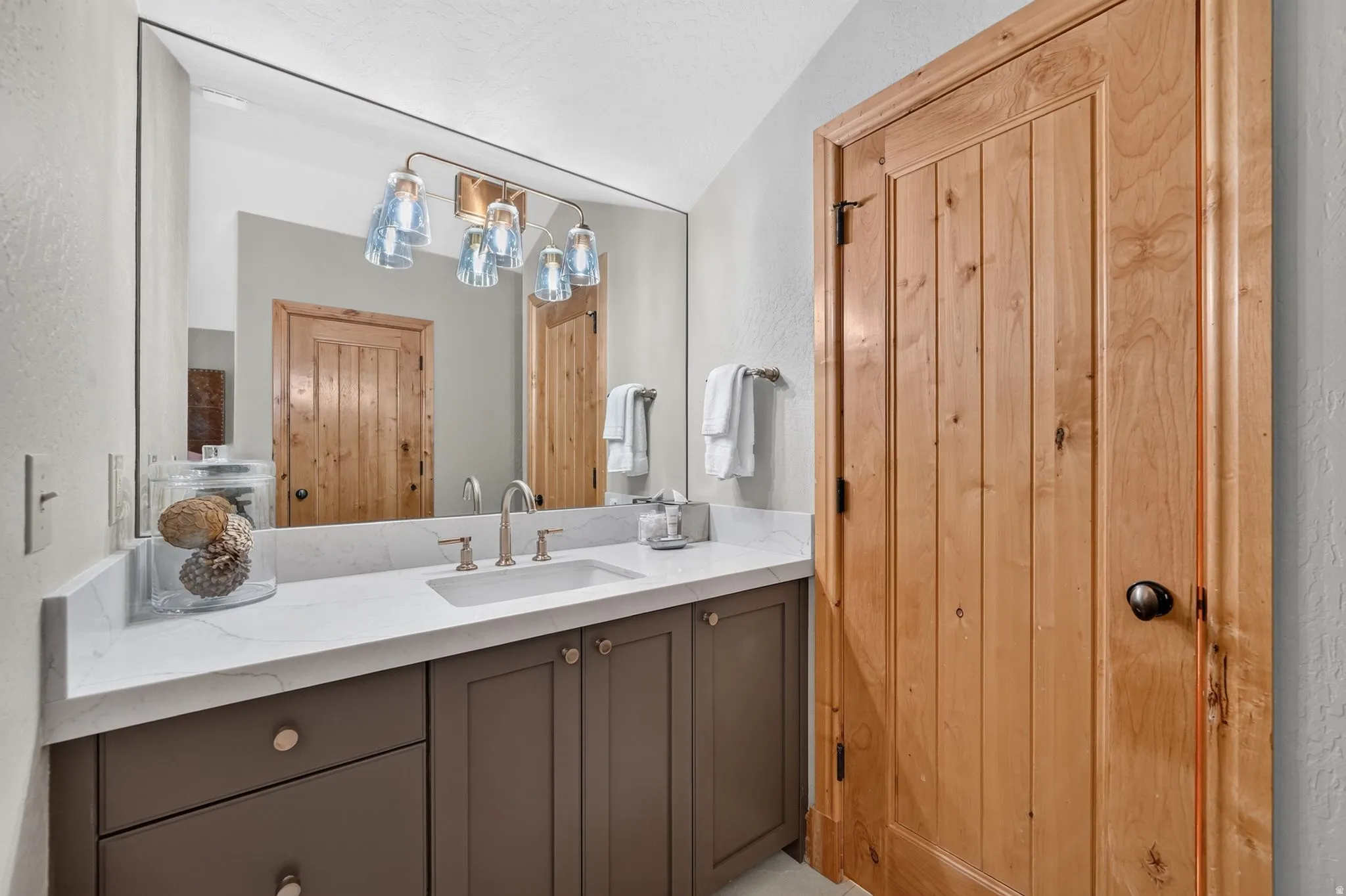 Bathroom vanity featuring an under-mount sink, brushed nickel faucet, and a quartz countertop