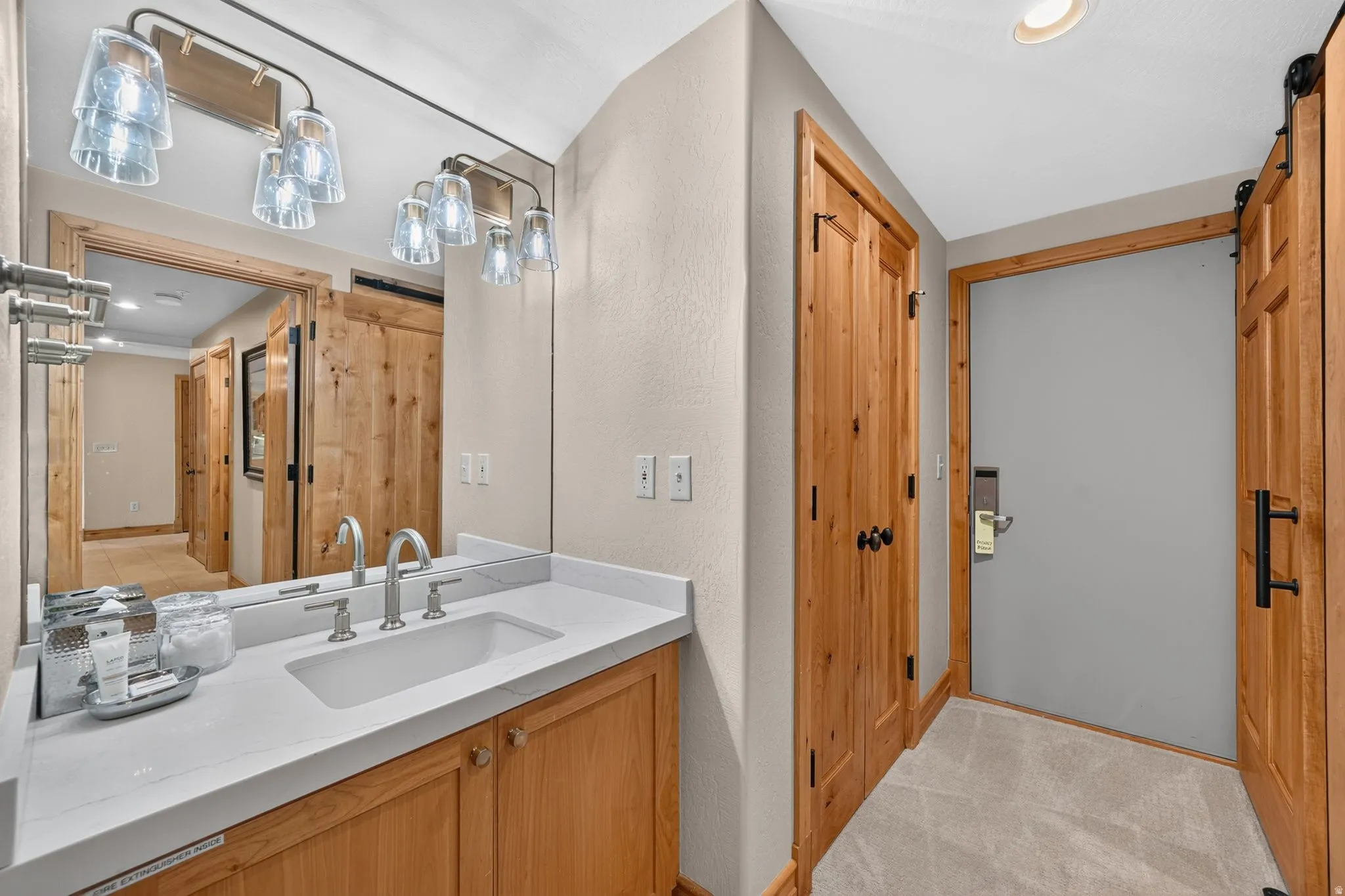 Bathroom vanity featuring an integrated sink with a brushed nickel faucet, a white countertop, and natural wood cabinetry