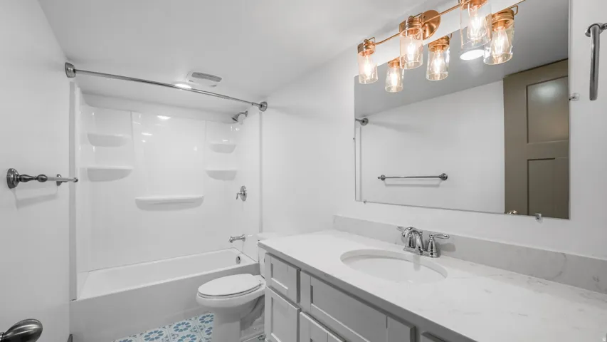 Contemporary bathroom featuring a white vanity with a light-toned countertop, an undermount sink, and chrome fixtures
