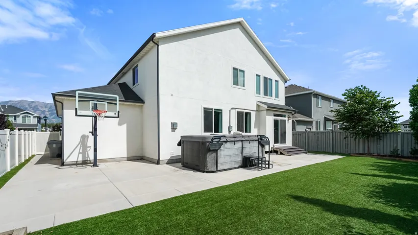 Expansive backyard featuring a large concrete patio, artificial turf lawn, and a privacy fence