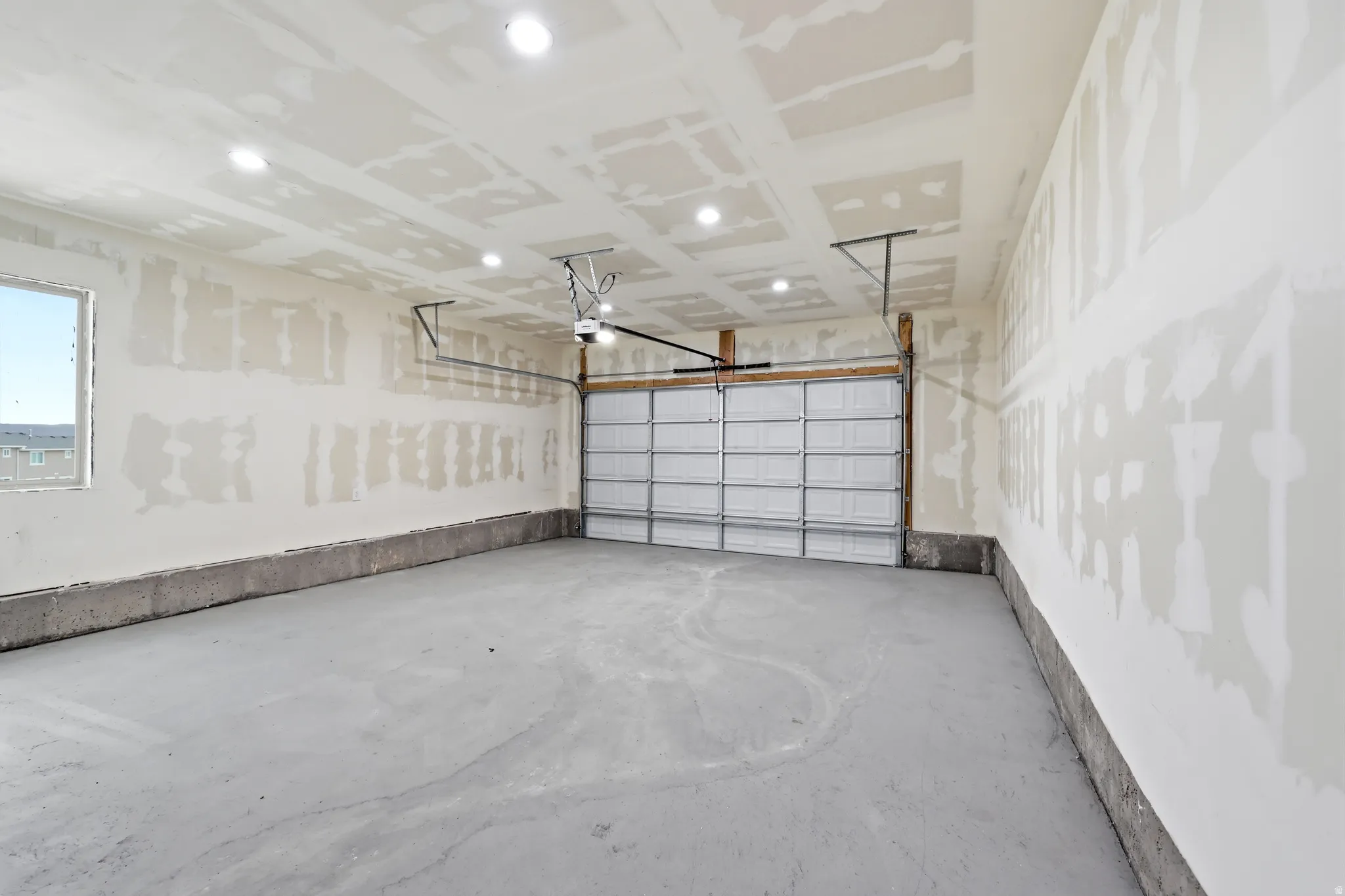 Spacious garage featuring a concrete floor, overhead lighting, and an automatic garage door opener
