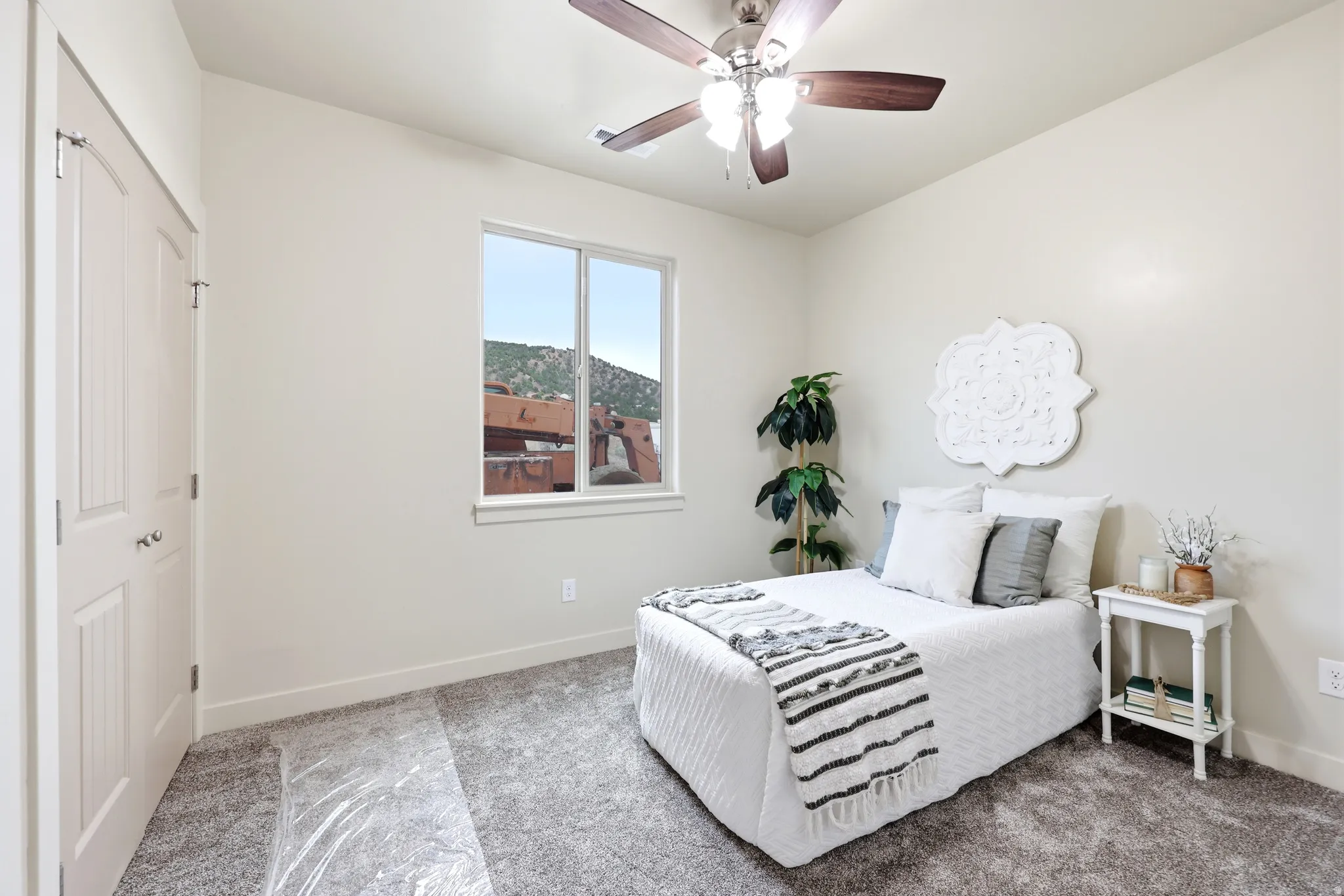 Bedroom featuring neutral wall paint, gray carpet flooring, a window with outdoor scenery, a ceiling fan with light fixture, and a white paneled closet door