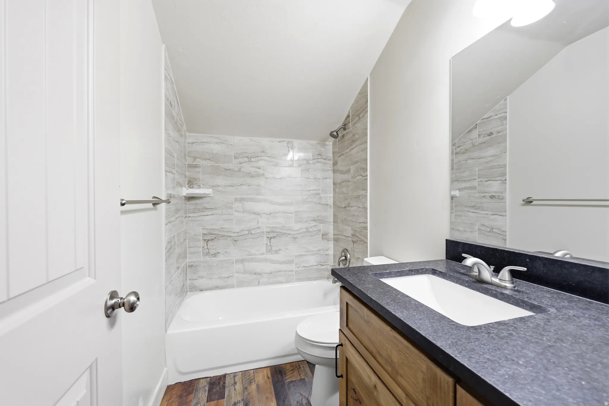 Bathroom featuring a single vanity with an integrated sink, dark textured countertop, and wood-finish cabinetry