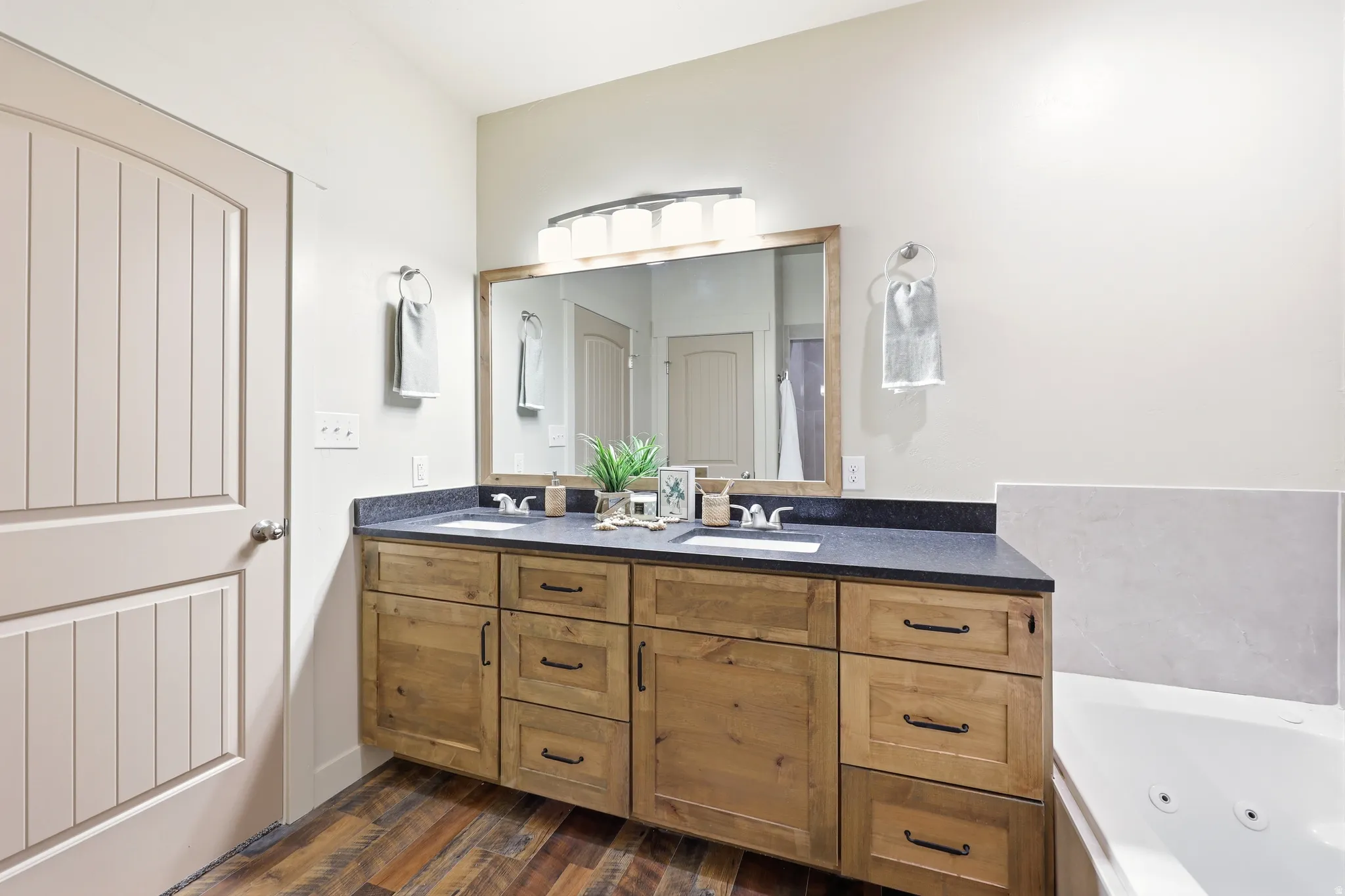 Dual vanity with wood cabinetry and dark countertops