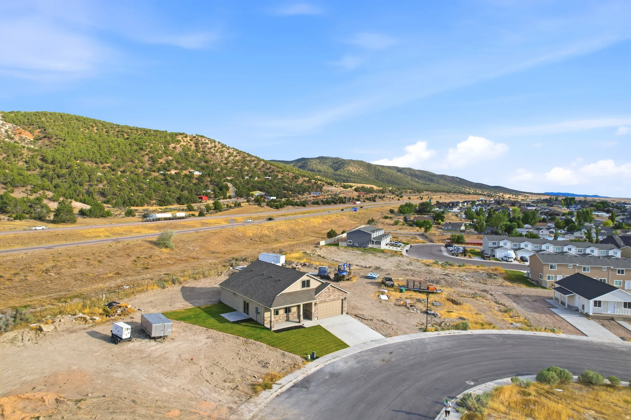 Newly constructed home featuring a stone facade and contrasting siding, an attached concrete driveway, and a partially landscaped lawn