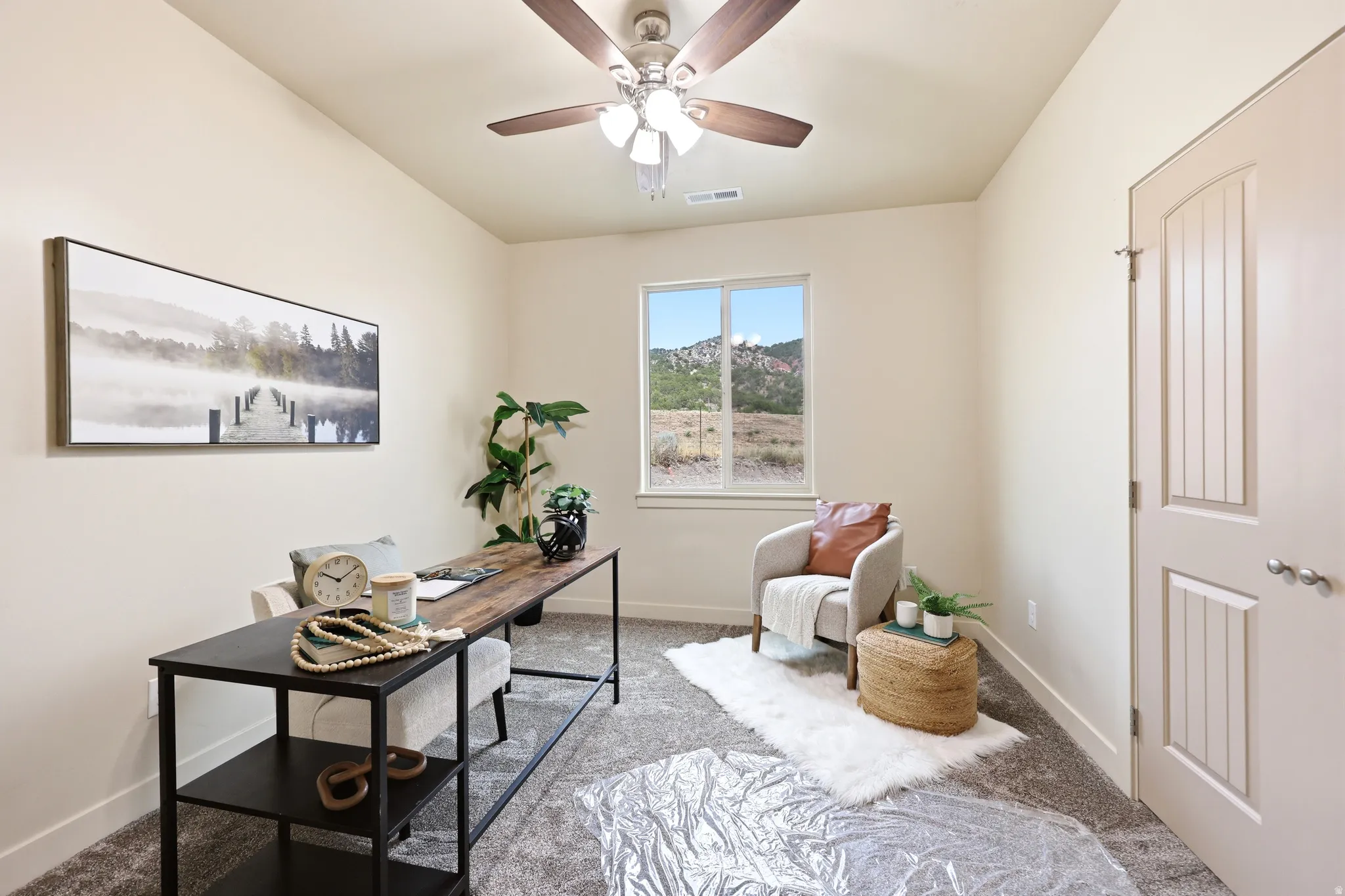 Interior space featuring a window with a mountain backdrop, ceiling fan, neutral wall tones, and carpeted flooring