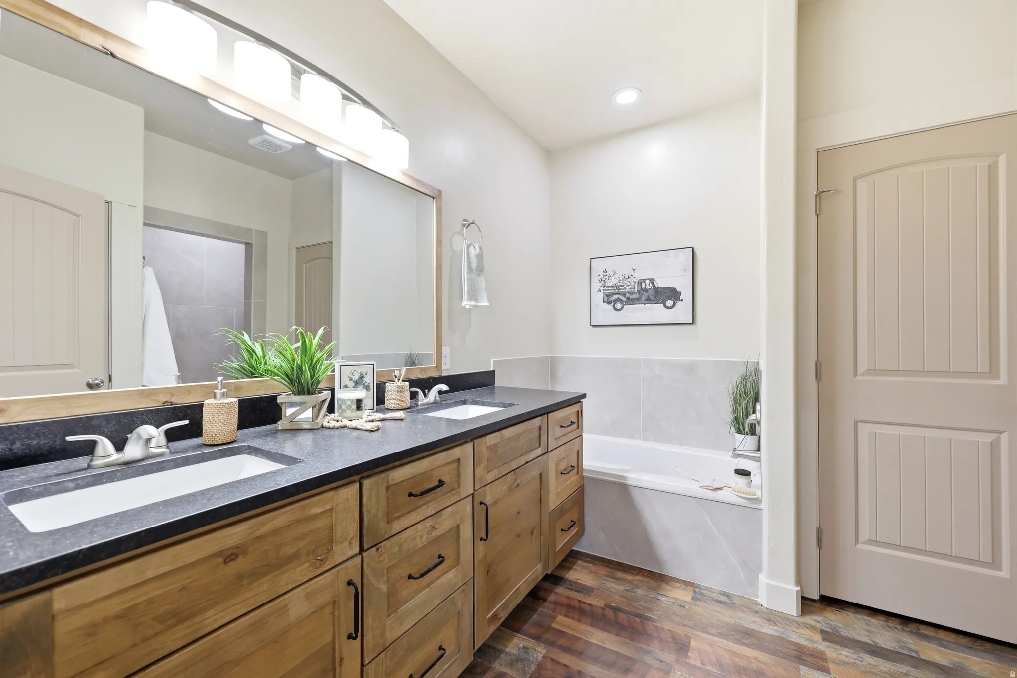 Double vanity with wood-finish cabinetry, dark countertops, and undermount sinks
