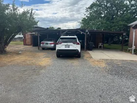 Gravel driveway providing access to a multi-vehicle carport and additional covered parking