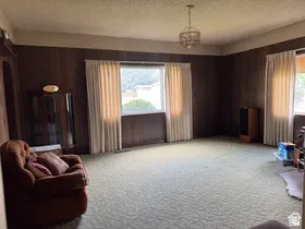 Spacious room featuring wood paneling, a textured ceiling, and a central chandelier