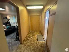 Hallway featuring textured carpet, recessed lighting, and two light wood-finish bi-fold doors