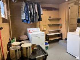 Utility area featuring exposed brick walls, a built-in clothing rod, and multiple wall-mounted shelves for storage