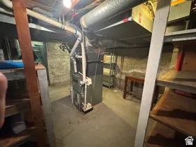 Utility area featuring a central HVAC unit with exposed ductwork, concrete flooring, and a concrete foundation wall