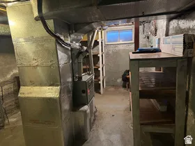 Basement utility area featuring exposed ductwork, a single window, and a built-in workbench