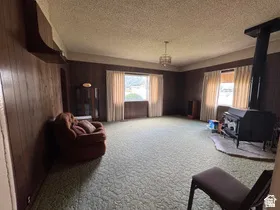 Spacious room with wood-paneled walls, light green carpet, and multiple windows